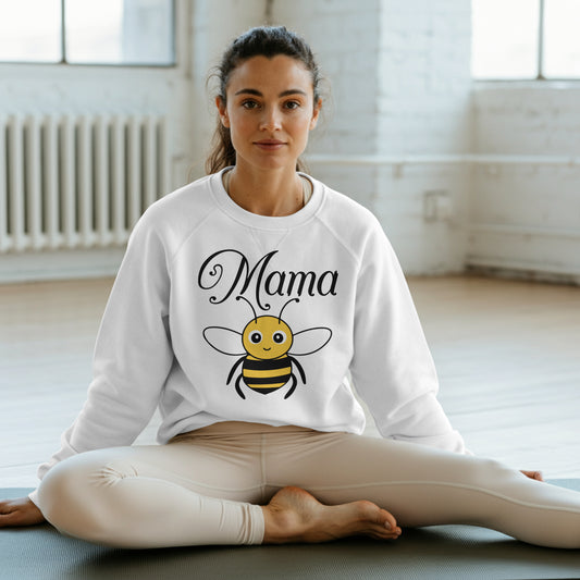 Woman sitting on a yoga mat wearing a white sweatshirt with a bee graphic and 'Mama' text.
