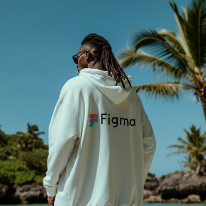 Person wearing a white hoodie with Figma logo against a tropical background