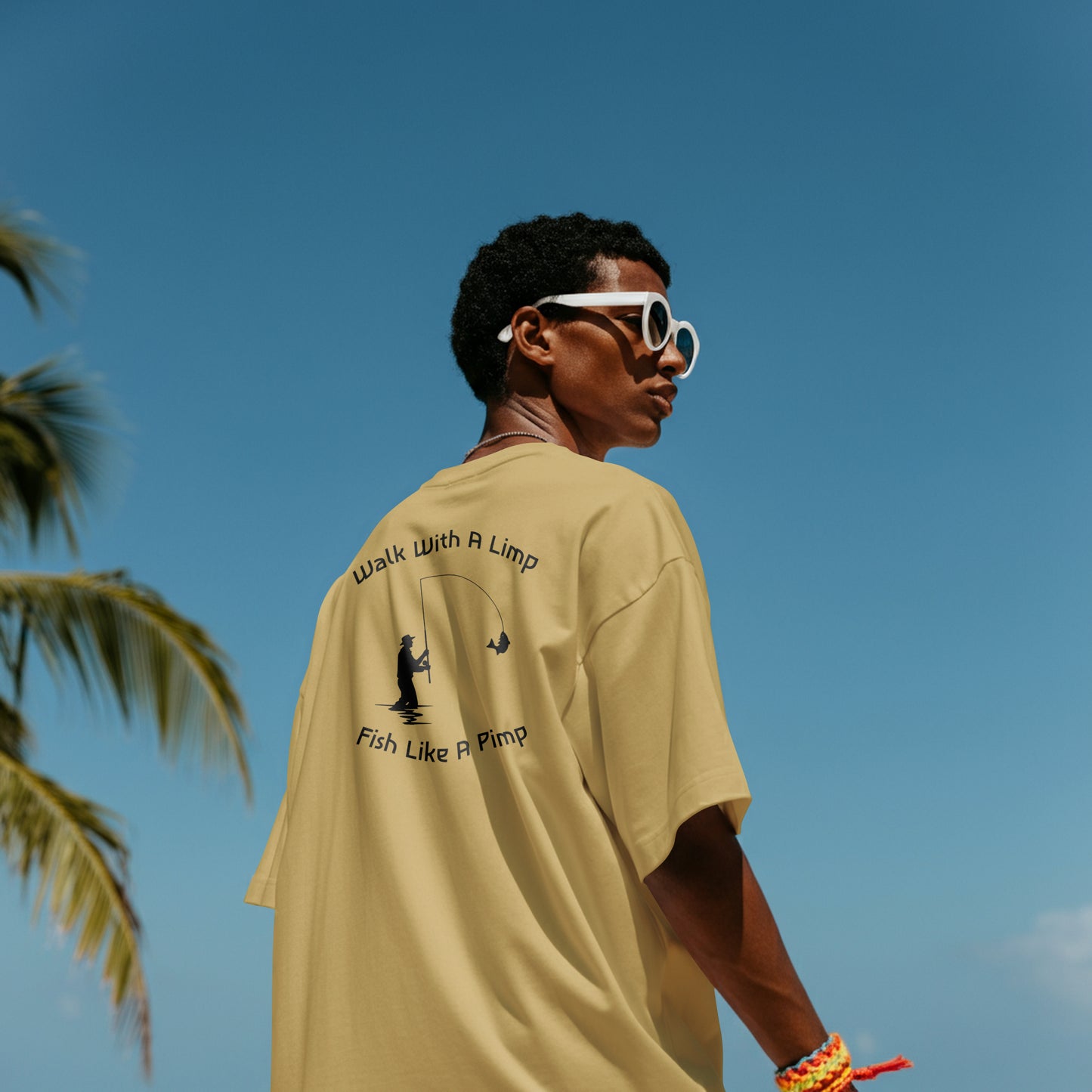 Person wearing a beige t-shirt with text and graphics, standing against a clear blue sky.