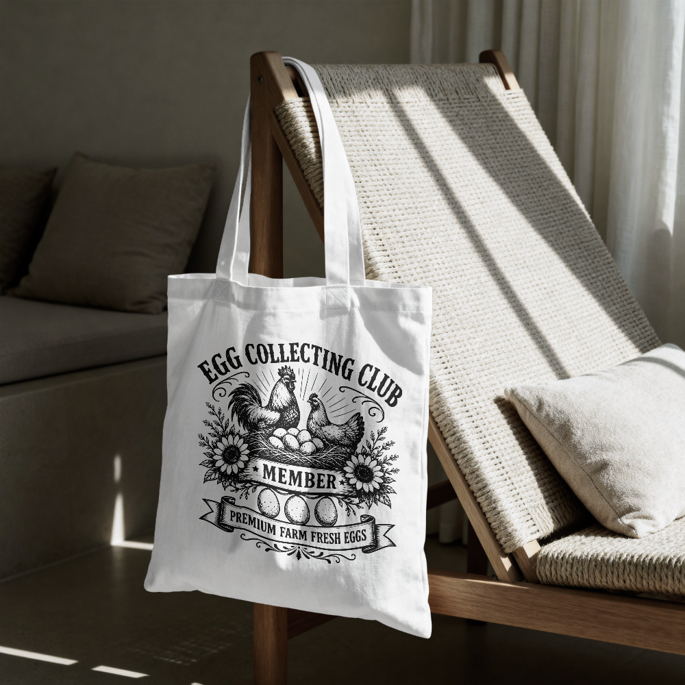 White tote bag with 'Egg Collecting Club' design on a wooden chair.