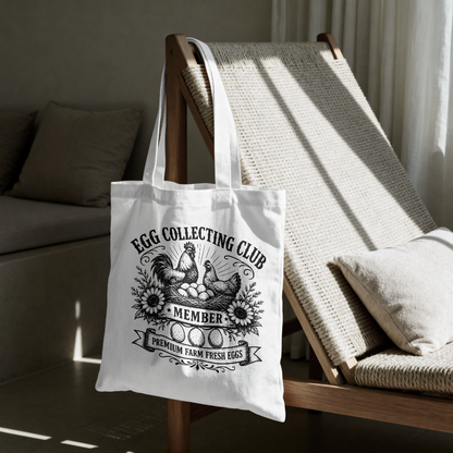 White tote bag with 'Egg Collecting Club' design on a wooden chair.