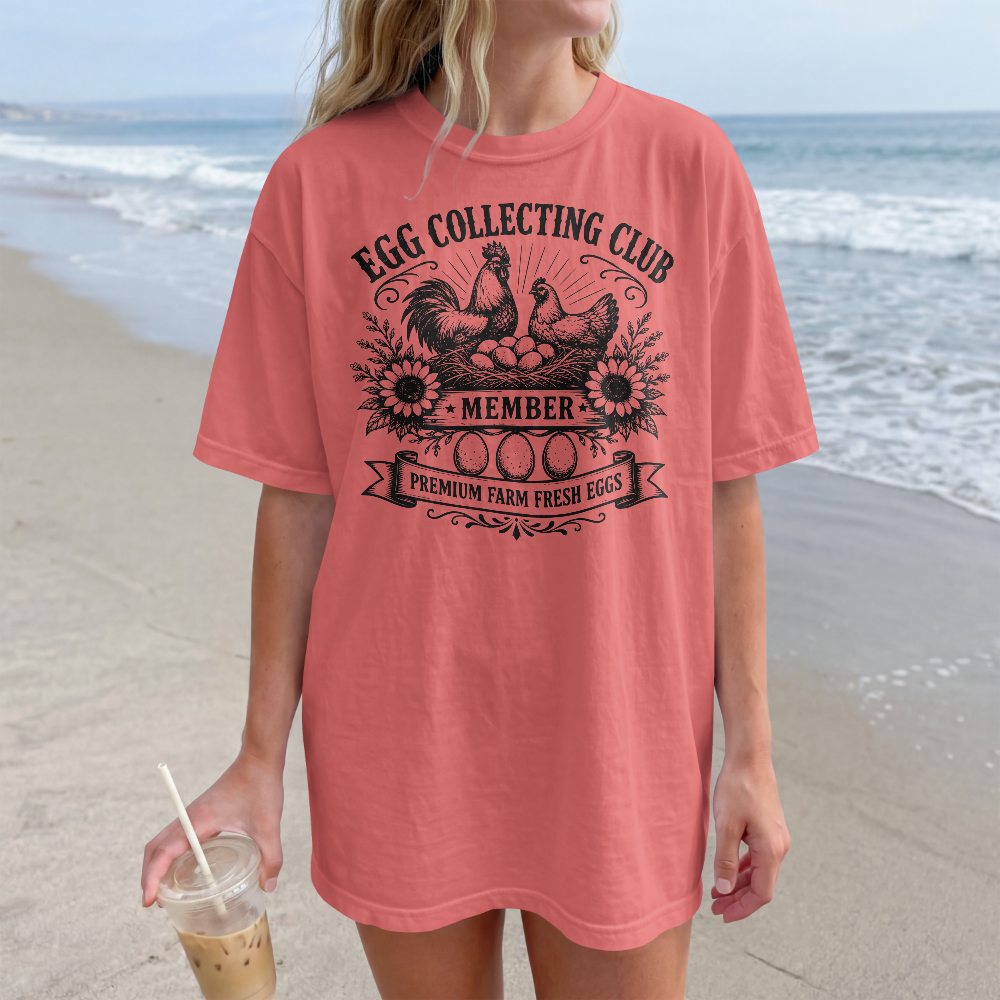 Person wearing a pink t-shirt with 'Egg Collecting Club' design on a beach.