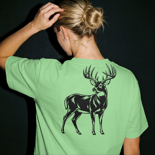 Person wearing a green t-shirt with a black deer graphic on the back against a dark background