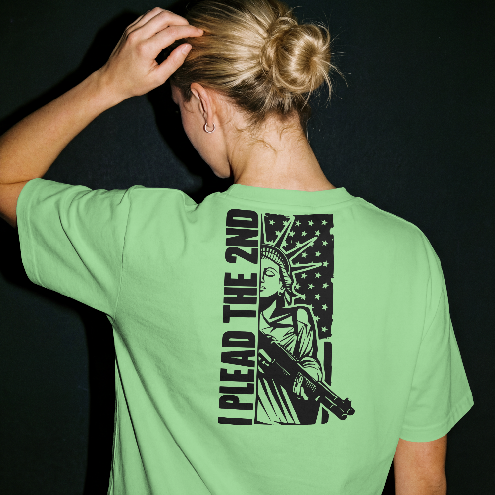 Person wearing a green t-shirt with a graphic design on the back, featuring the Statue of Liberty and text.