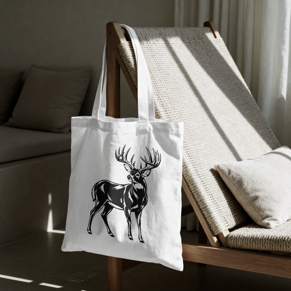 White tote bag with a black deer design on a wooden chair in a room.