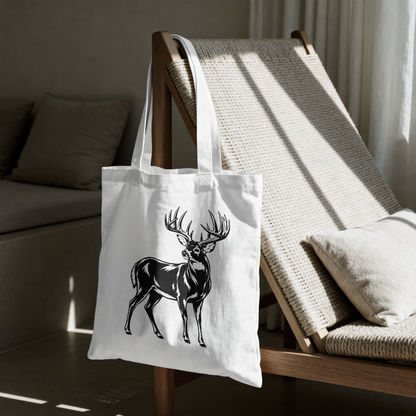 White tote bag with a black deer design on a wooden chair in a room.