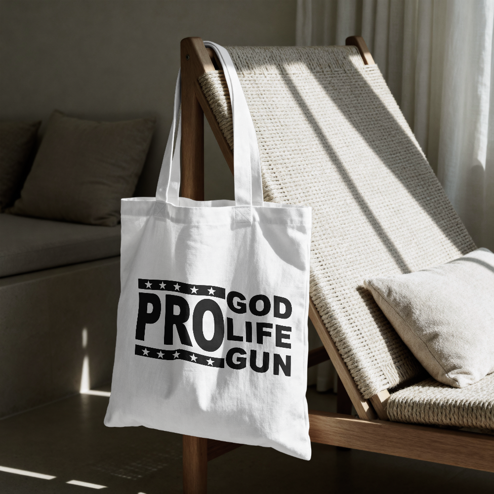 White tote bag with 'GOD PROLIFE GUN' text on a wooden chair in a room.