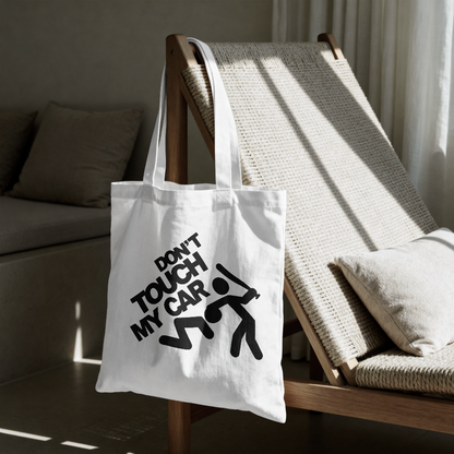 White tote bag with 'Don't Touch My Car' text on a wooden chair.