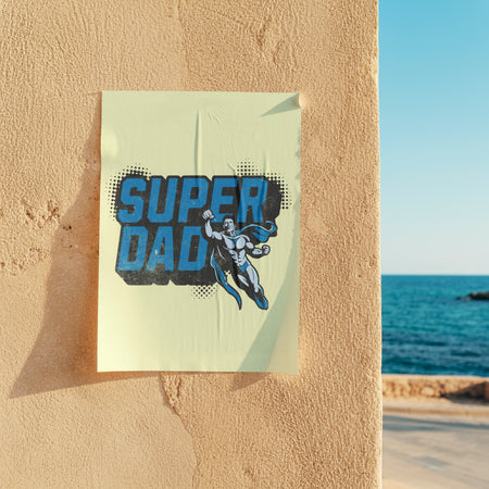 Poster with 'Super Dad' design on a wall by the ocean
