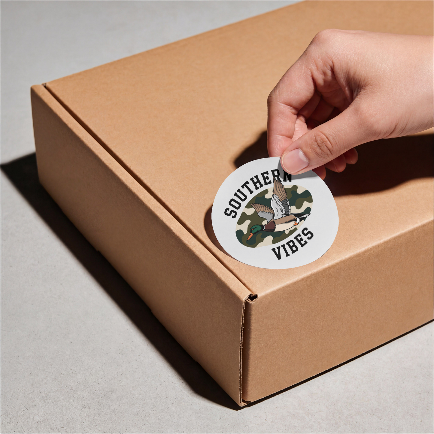 Hand placing a 'Southern Vibes' sticker on a cardboard box